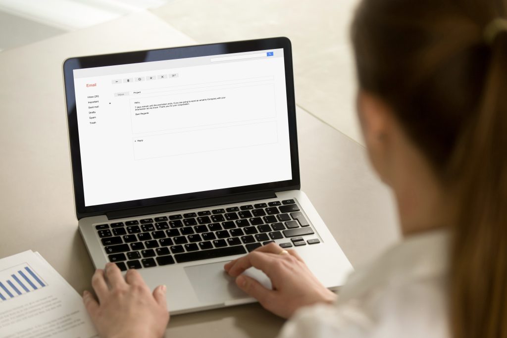 Businesswoman typing corporate e-mail using laptop at office des