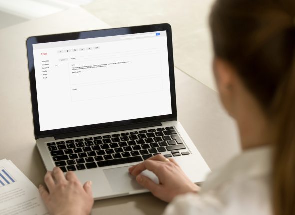 Businesswoman typing corporate e-mail using laptop at office des