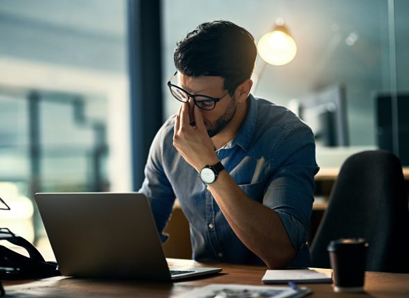 Burnout is killing his career. Shot of a young businessman experiencing stress during a late night at work.