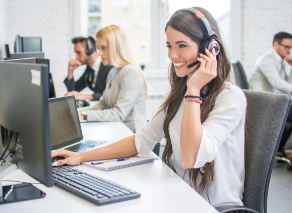 Friendly smiling woman call center operator with headset using c