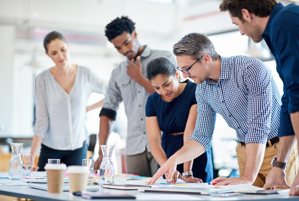 Theyve got planning down to a fine art. Mature man describing a plan of action to his diverse creative team.